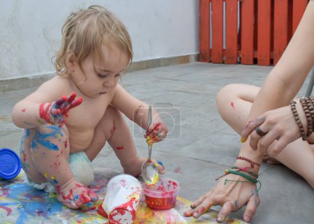 À la maison, un enfant et sa mère partagent une séance de peinture amusante, explorant les couleurs et les formes pour stimuler la créativité et l'apprentissage artistique