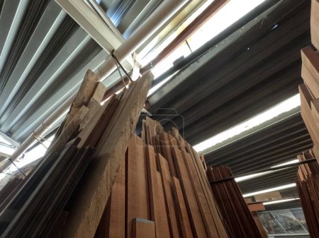 Foto de Madera aserrada con tableros verticales de madera tropical en un almacén industrial para la venta al público. - Imagen libre de derechos