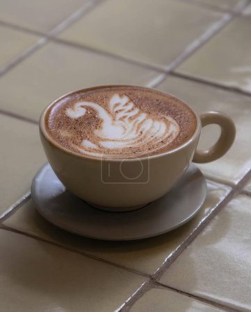 Téléchargez les photos : Tasse de café avec fond carrelé brun clair, cygne décorant la tasse cappuccino, latte boisson chaude - en image libre de droit