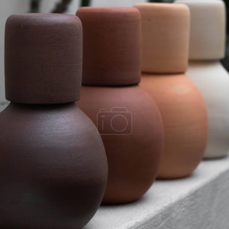 Photo for Vases for water, sugar and honey, terracotta colored ceramics, white metal table, restaurant accessories - Royalty Free Image