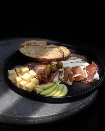 Foto de Plato de embutidos con queso, manzana agria, jamón serrano con aceitunas, pan tostado, mexico latin america - Imagen libre de derechos