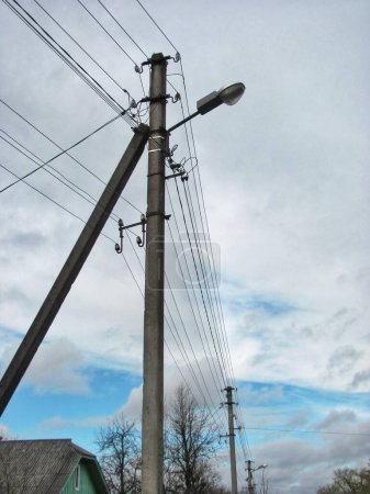Concrete utility pole with wires and a streetlight against a cloudy sky