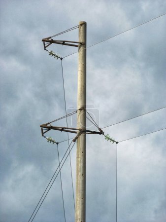 Vertical image of a concrete utility pole with wires and insulators