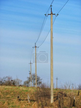 An electric pole standing tall in the middle of a field