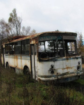 A forsaken bus decays amidst overgrown vegetation in a desolate Ukrainian landscape