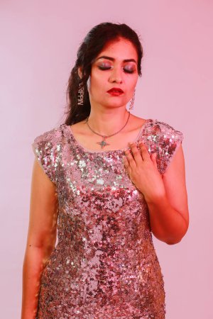 Foto de Atractiva, elegante, mujer con maquillaje en plata y collar, pendientes y accesorios de anillo posando en estudio de luz de neón. - Imagen libre de derechos