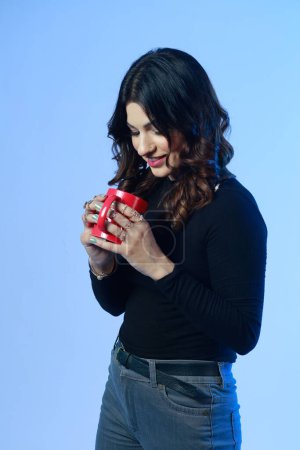 Foto de Mujer joven y fuerte en sudadera negra sosteniendo y bebiendo de la bebida caliente de la taza roja. Retrato aislado - Imagen libre de derechos
