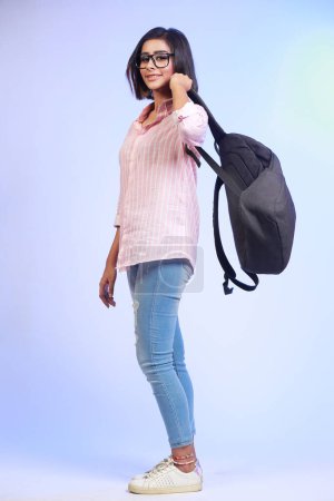 Photo for Full length profile shot of a female student in jeans and pink shirt with  bag - Royalty Free Image