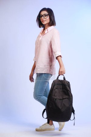 Photo for Full length profile shot of a female student in jeans and pink shirt with  bag - Royalty Free Image
