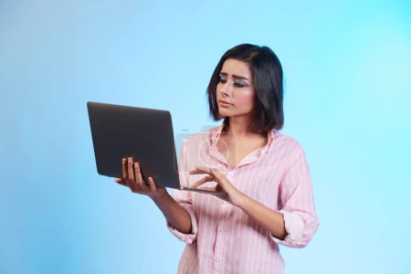 Téléchargez les photos : Jeune femme avec ordinateur portable sur fond bleu - en image libre de droit