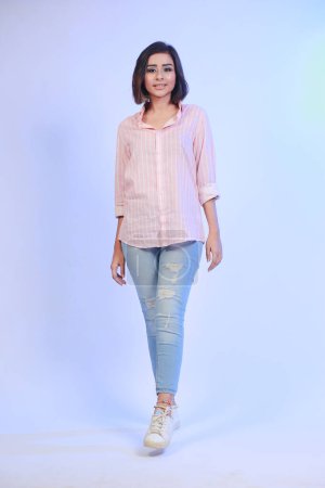 Téléchargez les photos : Full size photo of ecstatic girl wearing denim white sneakers and pink shirt isolated on blue gradient background - en image libre de droit