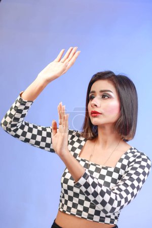 Téléchargez les photos : Asian young woman hand up cover face protect sun light and UV smile in studio shot isolated on blue background, female raising arm and hand in protection and block sunshine, sunscreen cream - en image libre de droit