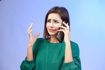 Photo for Young beautiful girl in a sweatshirt on a stressful phone call, expressive emotions and gestures of a tensed girl - Royalty Free Image