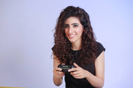 Photo for Cheerful girl with curly hair , deeply involved in playing video games, Enjoying her day off - Royalty Free Image