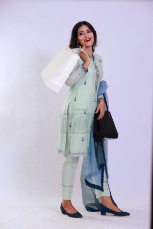 Foto de Mujer paquistaní feliz en Kameez Shalwar tradicional, llevando una bolsa de papel blanco de compras - Imagen libre de derechos
