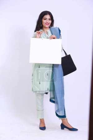 Foto de Mujer paquistaní feliz en Kameez Shalwar tradicional, llevando una bolsa de papel blanco de compras - Imagen libre de derechos
