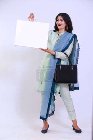Foto de Happy Pakistani woman in traditional Kameez Shalwar, carrying a shopping white paper bag - Imagen libre de derechos