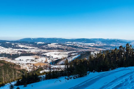 Photo for Stare Mesto town with Jeseniky mountains on the background from hiking trail bellow Kralicky Sneznik hill in Czech republic during winter day with clear sky - Royalty Free Image