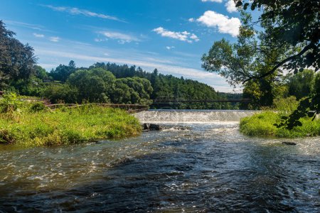 River with weir, bridge above and trees around during beautiful summer dsy with blue sky and clouds - Sazava river near Sazava village in Czech republic