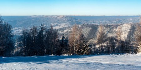 Frozen winter Beskids mountains with higjhest Lysa hora hill in Moravskoslezske Beskydy mountains in Czech republic - view from Zonka hill above Oscadnica village in Slovakia