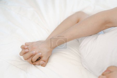Hände von ein paar schwulen Männern, die auf dem Bett miteinander verbunden sind. Sex und Leidenschaft. Zärtlichkeit und Schönheit. Zwei Männer lieben einander.