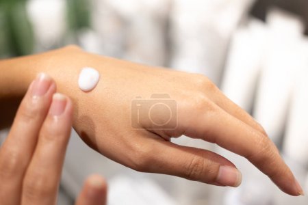 Frau testet und trägt Feuchtigkeitscreme in der Hand auf. Produkttests, Pflegekosmetik. Gesunde Hautpflege.