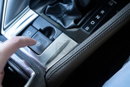 Dedo presionando el coche botón de freno de estacionamiento electrónico. Empuje / tire del dedo el freno de estacionamiento electrónico eléctrico con retención automática en el vehículo moderno.