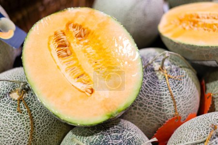 Photo for Man's hand picking a melon from the supermarket basket. sliced cantaloupe melon. - Royalty Free Image