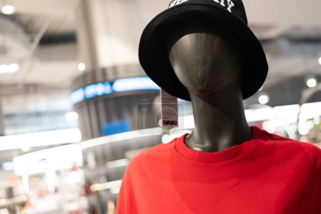 Téléchargez les photos : Mannequin portant le t-shirt rouge dans le magasin de vêtements. Mannequin portrait. - en image libre de droit