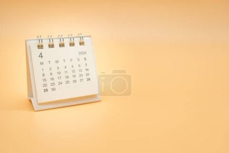 Calendario de escritorio sencillo para ABRIL 2024 aislado sobre fondo naranja. Concepto de calendario con espacio de copia.