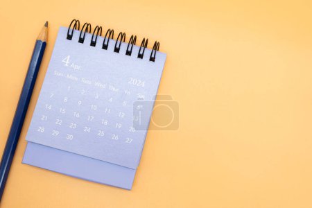 2024 Abril Calendario y lápiz aislados sobre fondo naranja. planificación para el concepto de negocios o viajes. Copiar espacio para texto.