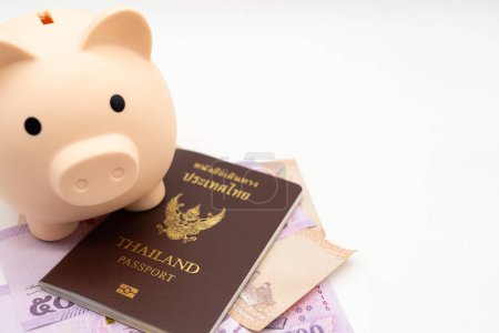 Sparschwein, thailändischer Pass und thailändisches Geld für Reisen in abgeschiedene Gegenden. Die Thailänder bereiteten sich auf ihren Urlaub in Japan vor. Reisefonds. Sparen für den Urlaub.