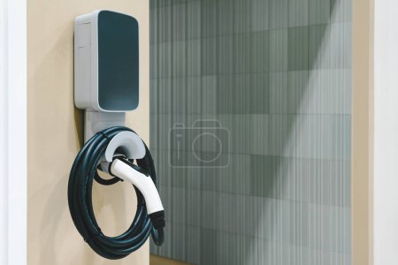 Electric car small home wall charger with cable. Plug for vehicle with electric engine. EV charger. Clean energy. Charging point at car parking lot. Future transport technology.