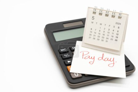 Hand writing text PAY DAY on May 2024 calendar with calculator in isolated background. Reminder concept of payment. copy space.