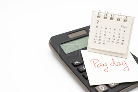 Hand writing text PAY DAY on July 2024 calendar with calculator in isolated background. Reminder concept of payment. copy space.