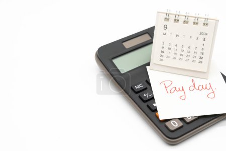 Hand writing text PAY DAY on September calendar with calculator in isolated background. Reminder concept of payment. 