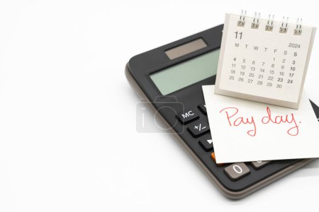 Hand writing text PAY DAY on November calendar with calculator in isolated background. Reminder concept of payment. copy space.