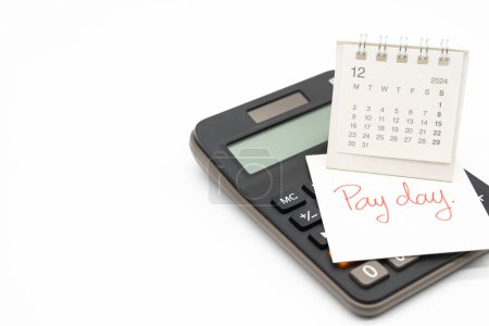 Hand writing text PAY DAY on December calendar with calculator in isolated background. Reminder concept of payment. copy space.