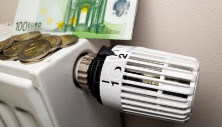 Rising cost of heating and electricity in Europe. Heating radiator with thermostat on which euros lie. Rising energy prices. Energy crisis and recession. 2 euro coins and 100 euro banknotes