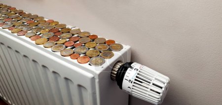 Photo for The concept of the high cost of heating around the world. There are a lot of euro coins on a heating radiator with a temperature regulator - Royalty Free Image