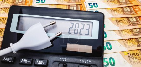Stecker und Taschenrechner auf dem Hintergrund einer großen Anzahl von 50-Euro-Scheinen. Das Konzept der hohen Stromkosten, Inflation und Krise im Jahr 2023