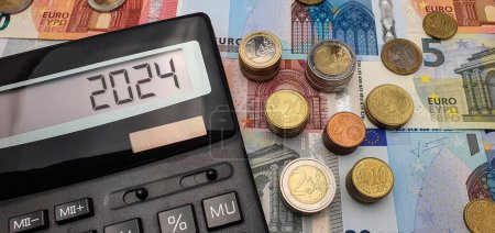 Promising prospects for euro strengthening in 2024. An abundance of banknotes, coins and a calculator symbolize financial growth. The calculator screen displays the year 2024