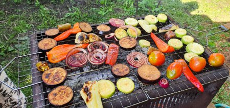 Photo for Outdoor BBQ grilling with a variety of vegetables. Grill cooking in the great outdoors. Vegetables are fried on the grill: Bulgarian and hot peppers, zucchini, eggplant, onions and tomatoes - Royalty Free Image