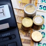 Energy and financial crisis in Europe in 2024. The ever-increasing cost of energy, food and goods. Calculator and a lot of euro coins on the background of banknotes of 50 euros