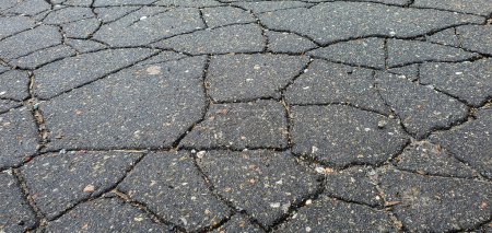 Cracks in the asphalt on the highway. Old road with cracked, damaged, destroyed, worn, broken, dirty asphalt. The sidewalk and roadway part for transport needs repair. Cracked bitumen