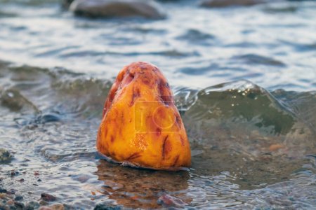 Téléchargez les photos : Un grand morceau jaune d'ambre dans l'eau de mer avec des vagues - en image libre de droit