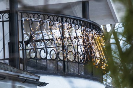 Téléchargez les photos : A balcony with black railings, yellow lights and green trees - en image libre de droit