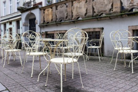 Foto de Terraza exterior con mesas de krnas blancas y sillas en pavimento de piedra - Imagen libre de derechos