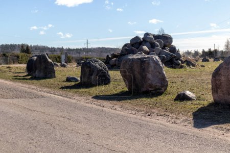 Large stone blocks stacked on the side of a gravel road and a pile of stones in the background