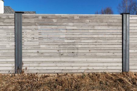 Wooden board fence with a stone and metal post in the middle